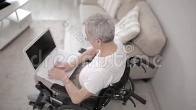 灰头土脸的男人<strong>坐在</strong>他的病房里的轮椅上，<strong>坐在</strong>笔记本<strong>电脑前</strong>。